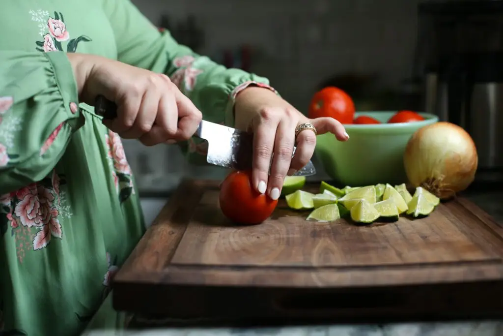 Hailey cutting vegetables on a wooden cutting board in her kitchen