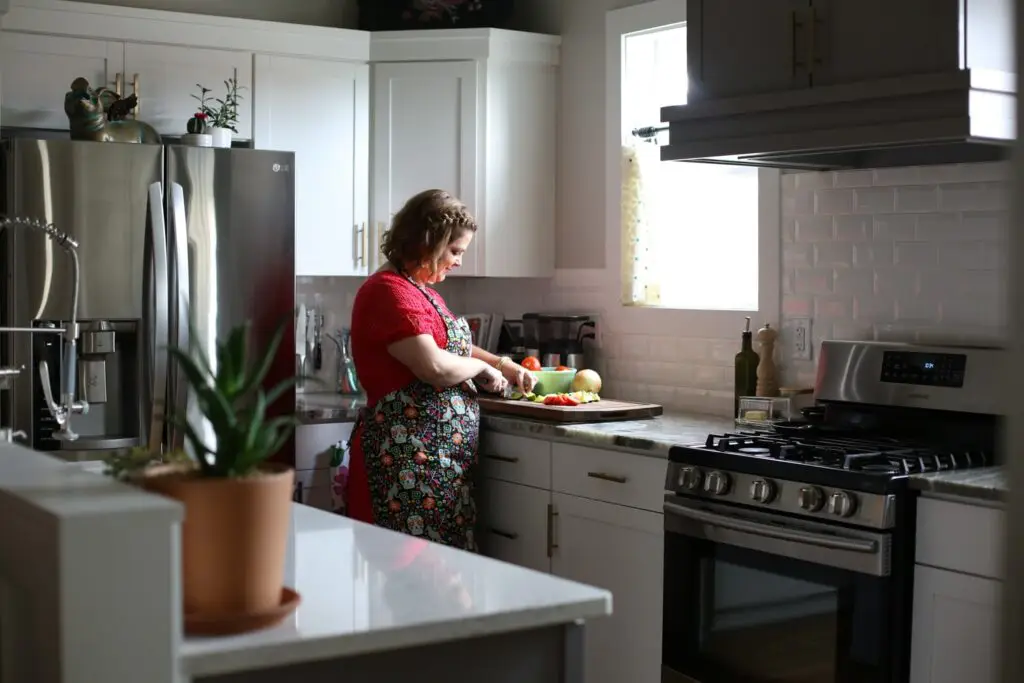 Hailey cutting vegetables on a wooden cutting board in her kitchen