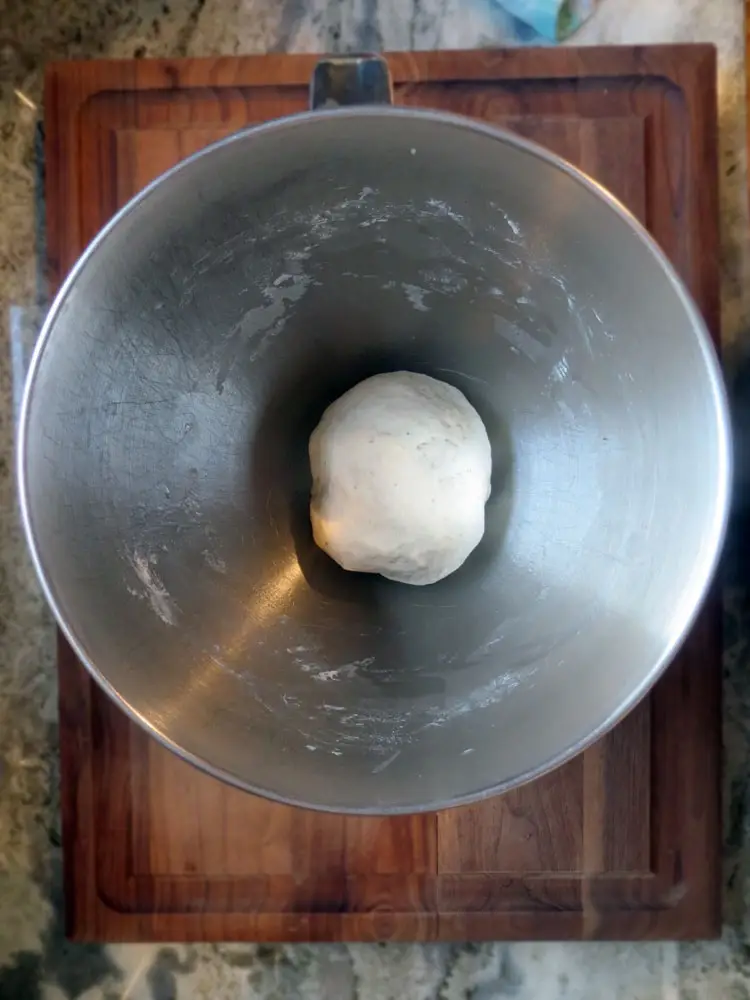 a small ball of uncooked dough in a large metal bowl