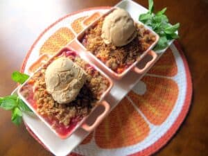two individual servings of peach crumble each topped with a scoop of ice cream
