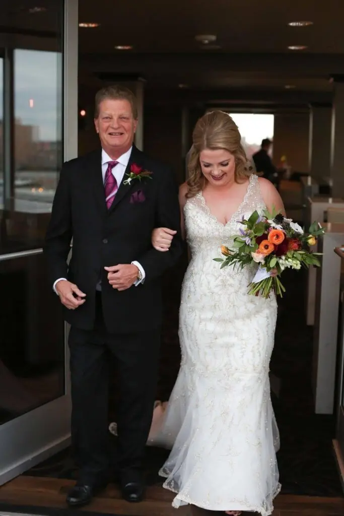 Adult man in a black suit walking with young adult female in a wedding dress