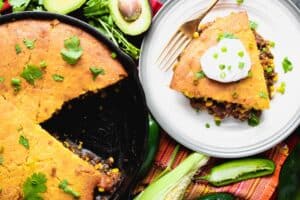A sour cream topped wedge of cornbread over a mixture of meat and vegetables