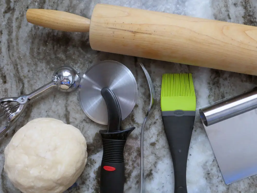 kitchen tools and a ball of dough on a marbled surface