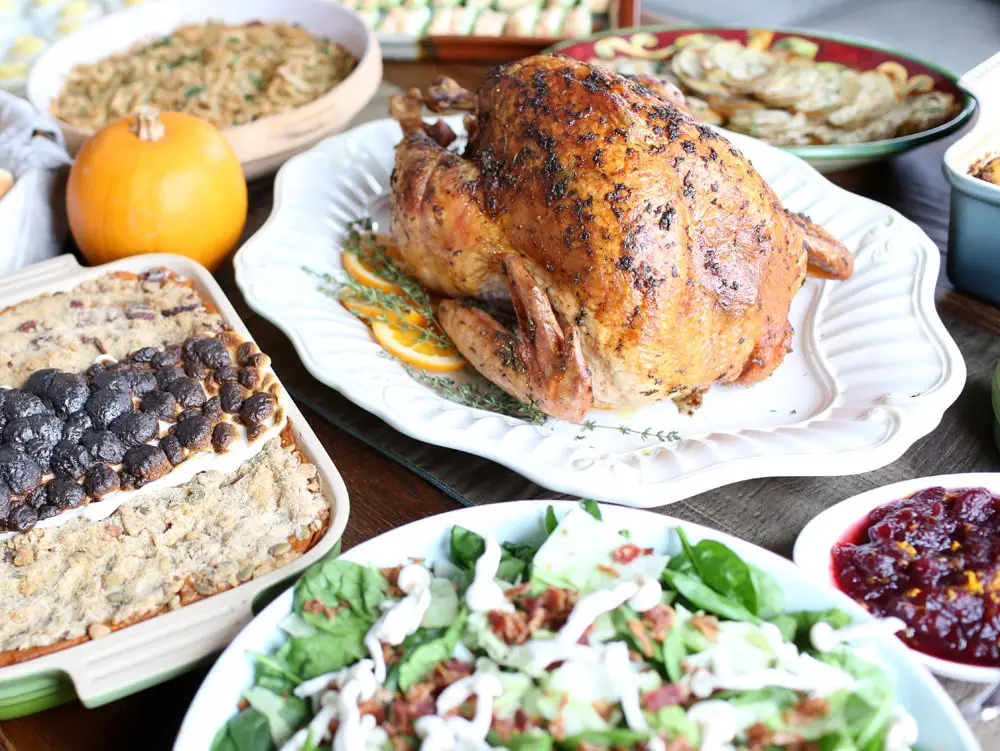 Thanksgiving herb butter turkey surrounded by side dishes on a Thnksgiving table