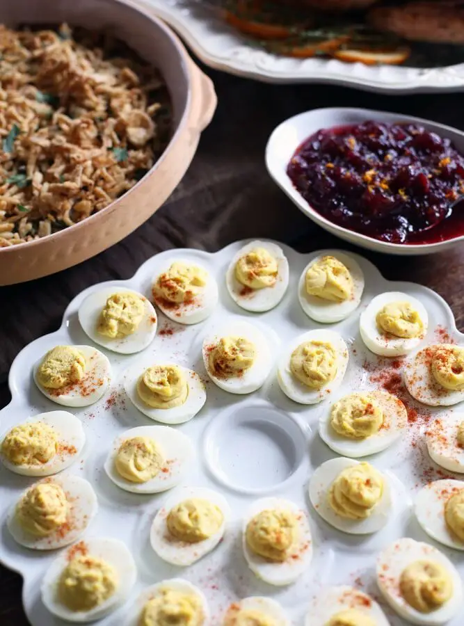 a tray of deviled eggs surrounded by other Thanksgiving side dishes