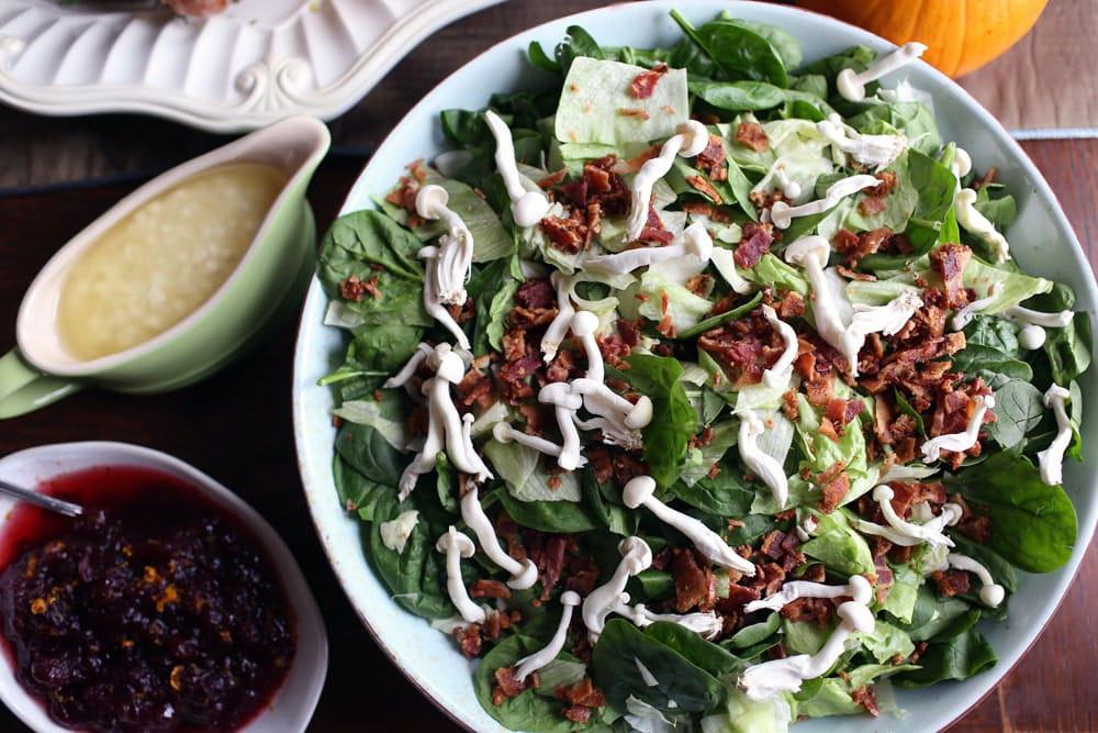 salad topped with wild mushrooms and bacon bits in a white bowl