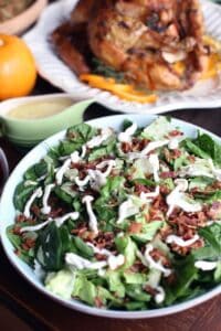 a bacon and mushroom spinach salad in a round white bowl