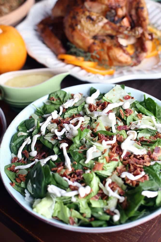 a bacon and mushroom spinach salad in a round white bowl