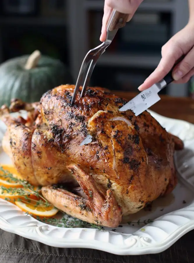 a Thanksgiving turkey being carved with a meat fork and a metal knife