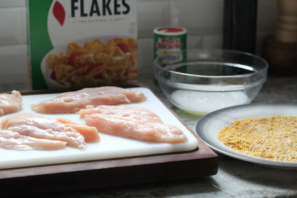 chicken cutlets on a white cutting board aside dredging ingredients