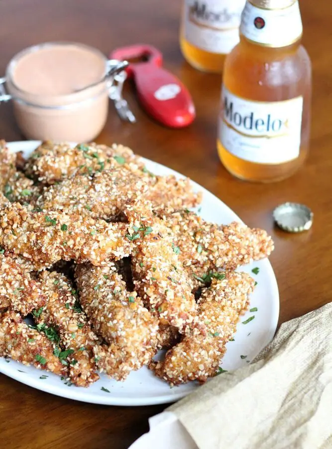 cornflake crusted chicken tenders stacked on an oval plate