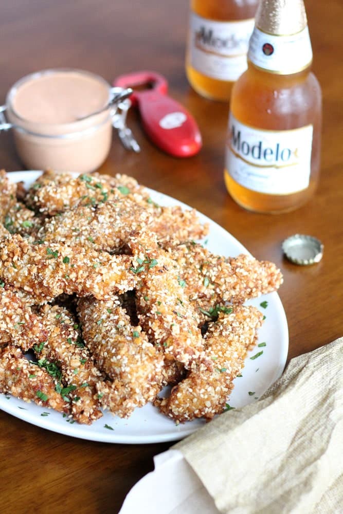 cornflake crusted chicken tenders stacked on an oval plate