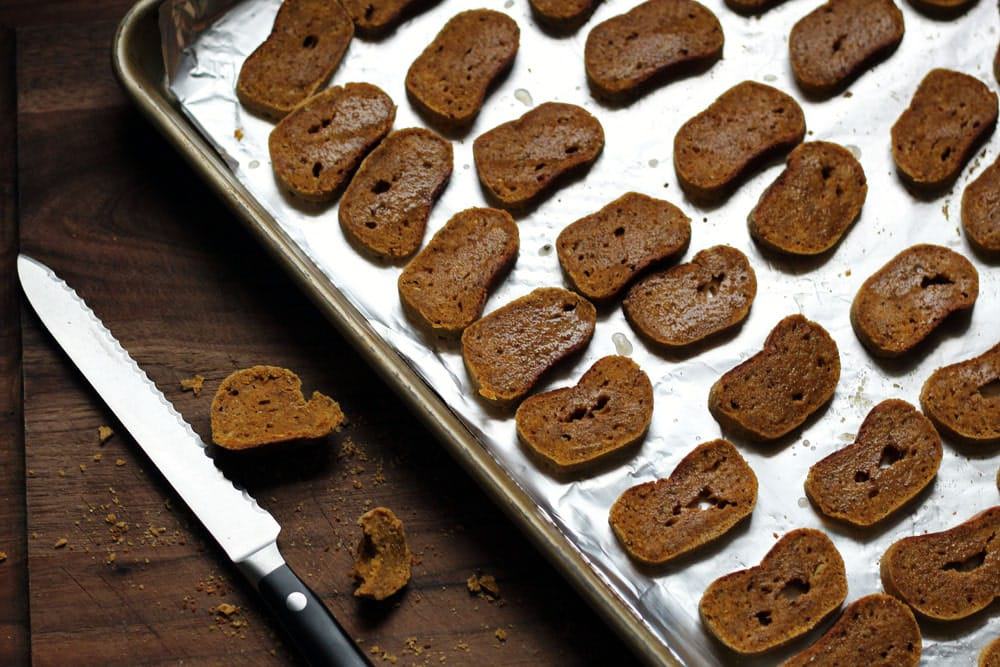 thin slices of brown biscuits on a foil lined metal baking sheet