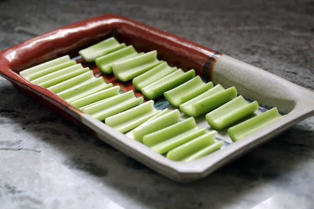 portions of celery lined side by side on a stone serving dish