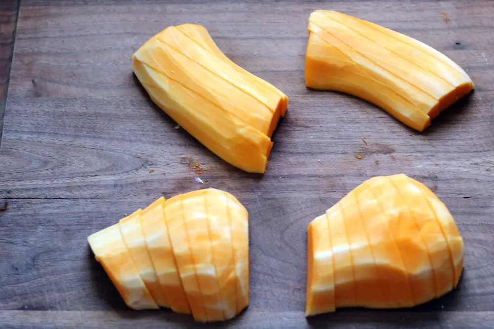 sliced peeled butternut squash on a wooden cutting board