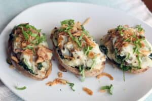 three baked potatoes stuffed and topped with French fried onions and thinly cut green herbs