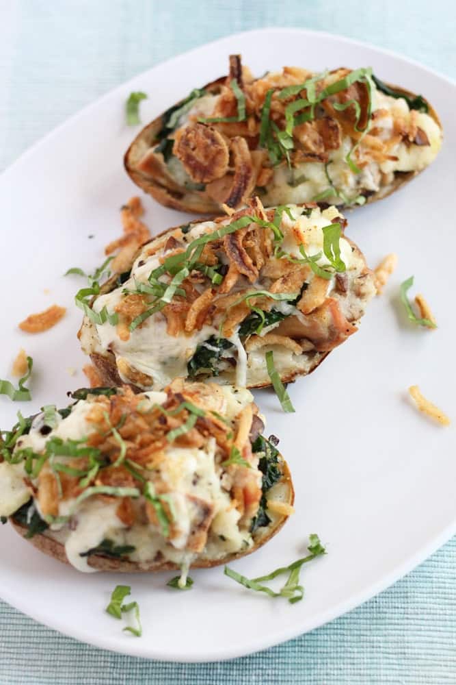 three chicken florentine stuffed baked potatoes on a white platter