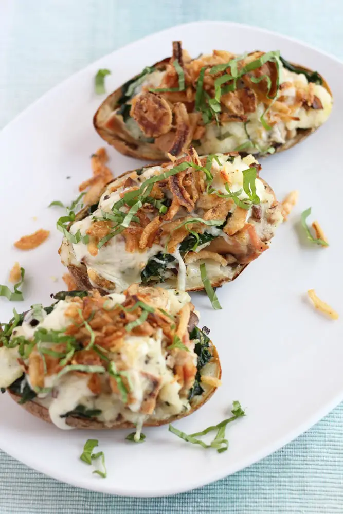 three chicken florentine stuffed baked potatoes on a white platter