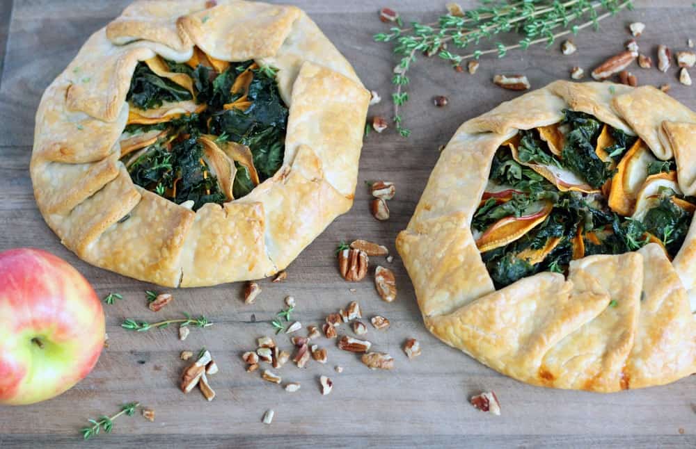 two flat round pastries with greens and sliced vegetables in the center