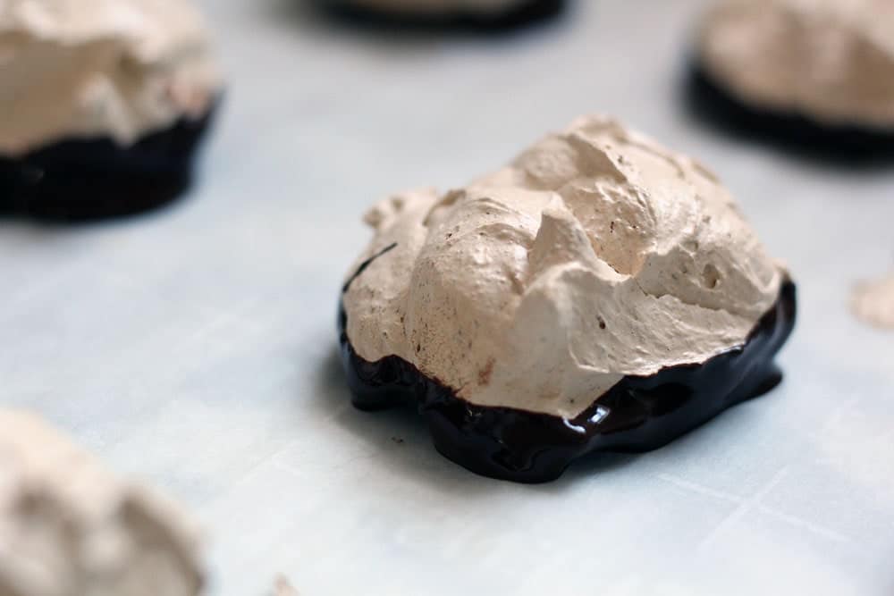 freshly dipped light brown mocha & chocolate meringue cookies on parchment paper