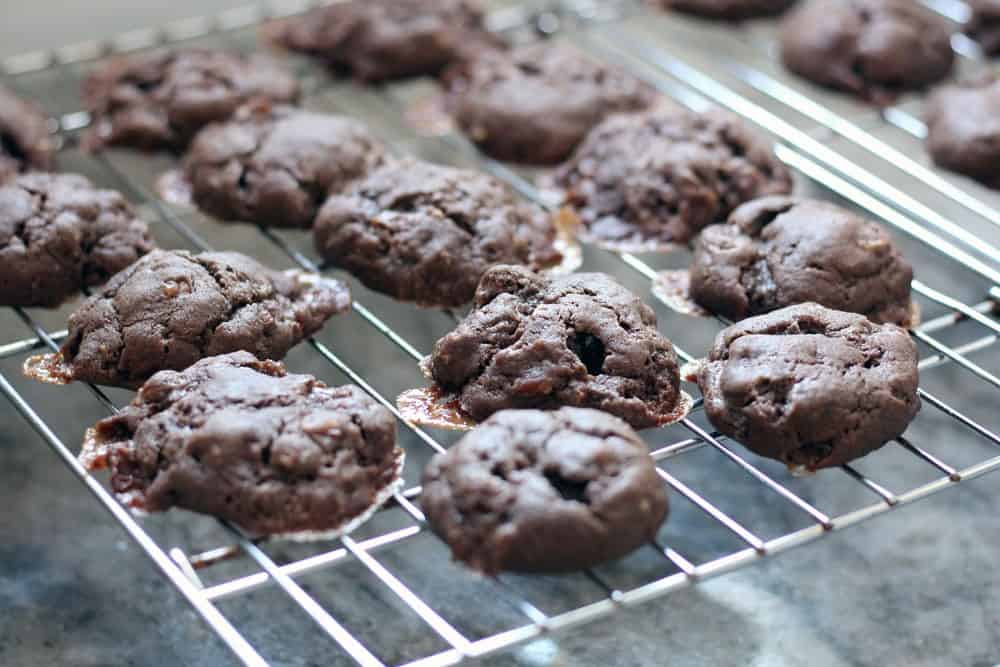 brown cookies cooling on a wire rack over a marbled countertop