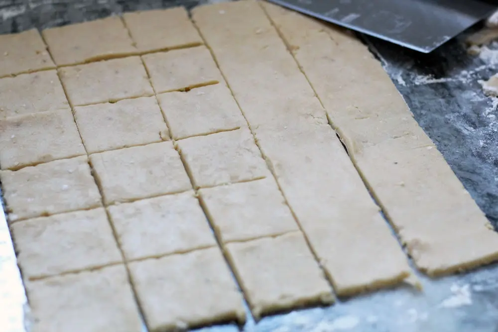 a sheet of cookie dough being scored into squares