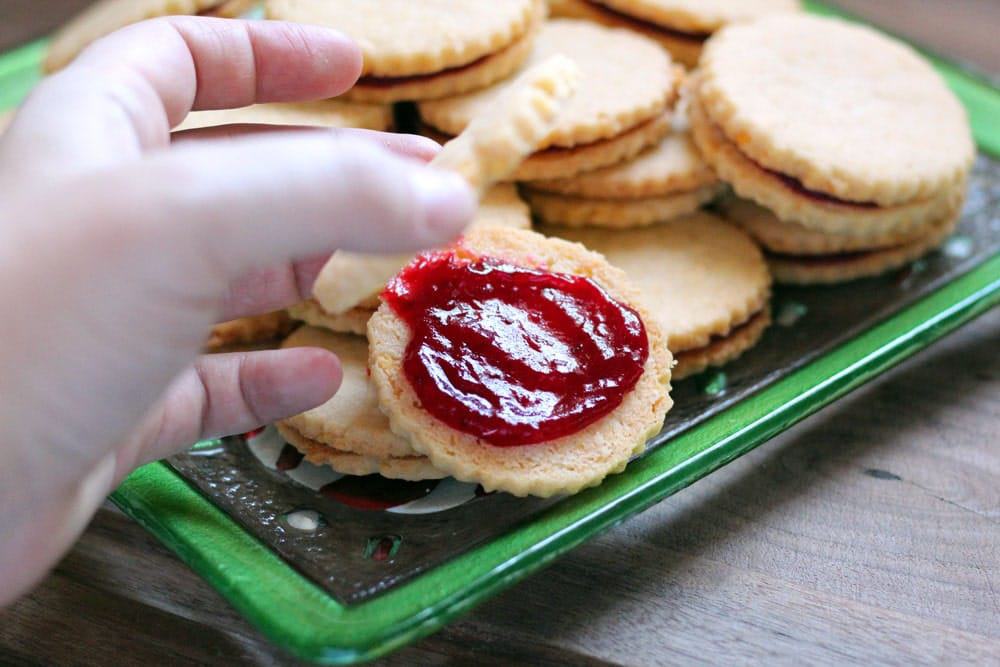 sandwich cookies spread with cranberry filling on a green platter