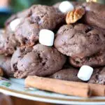chocolate cookies on a christmas patterned plate garnished with marshmallows and pecans