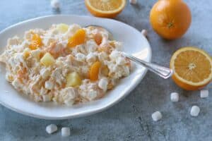 an ambrosia salad of pineapple, oranges and marshmallows in a white bowl