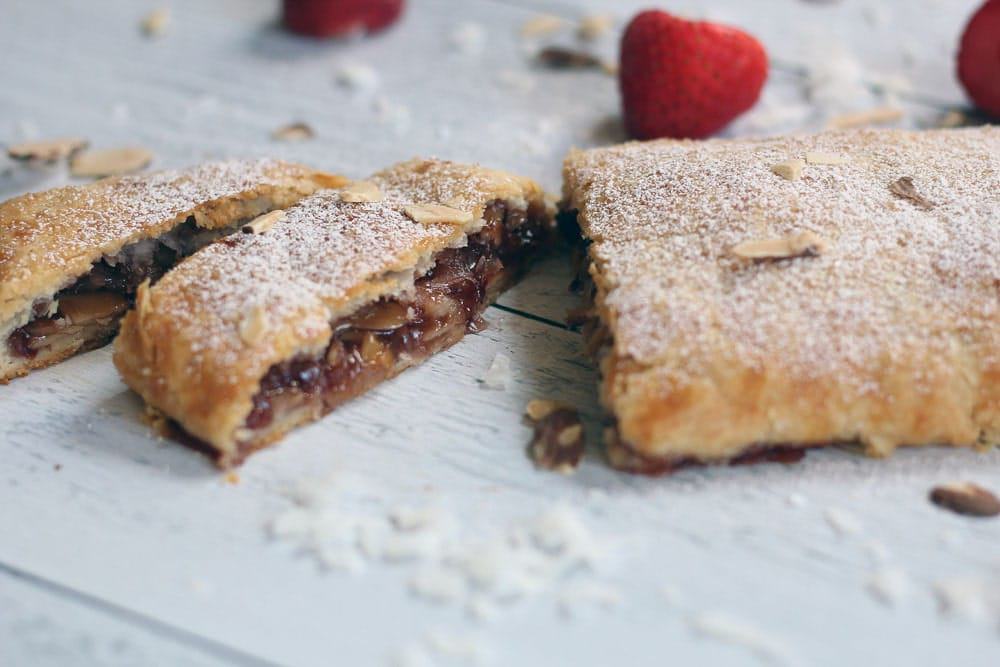 slices cut from a baked strawberry almond streudel dusted with powdered sugar