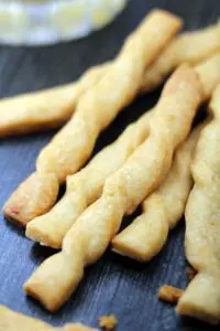 a pile of twisted golden brown baked bread stick style pastries on a wood surface