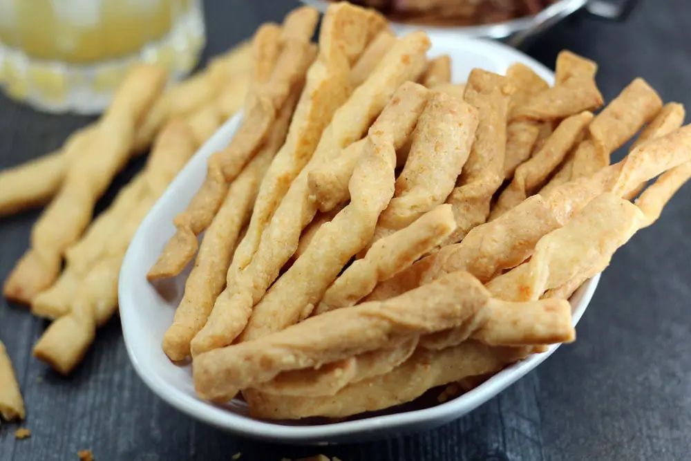 a white bowl filled with baked gouda cheese straws