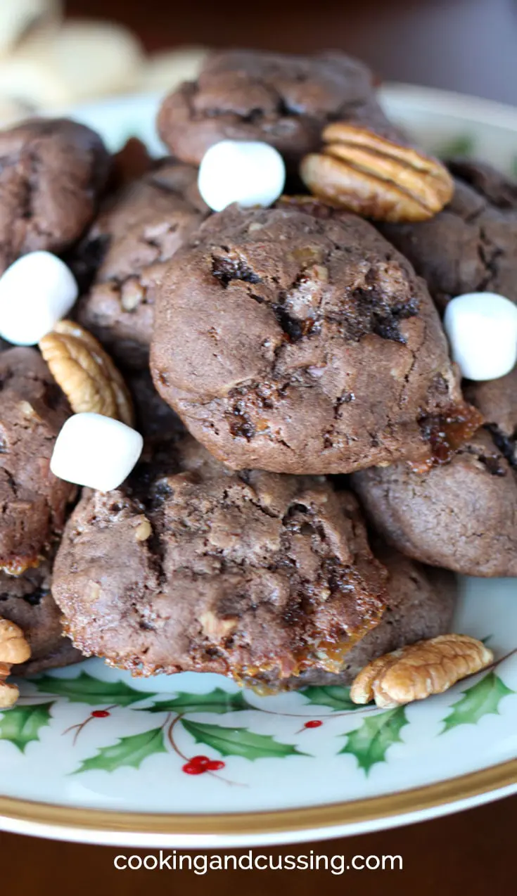 chocolate cookies on a christmas patterned plate garnished with marshmallows and pecans