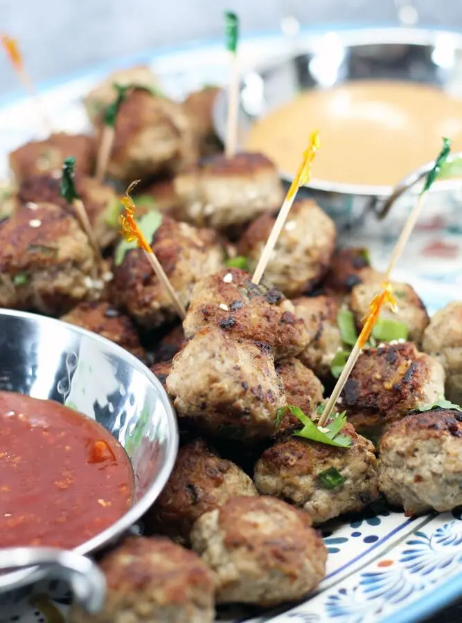 Pork and Mushroom Meatballs piled on a platter with bowls of orange and red sauces
