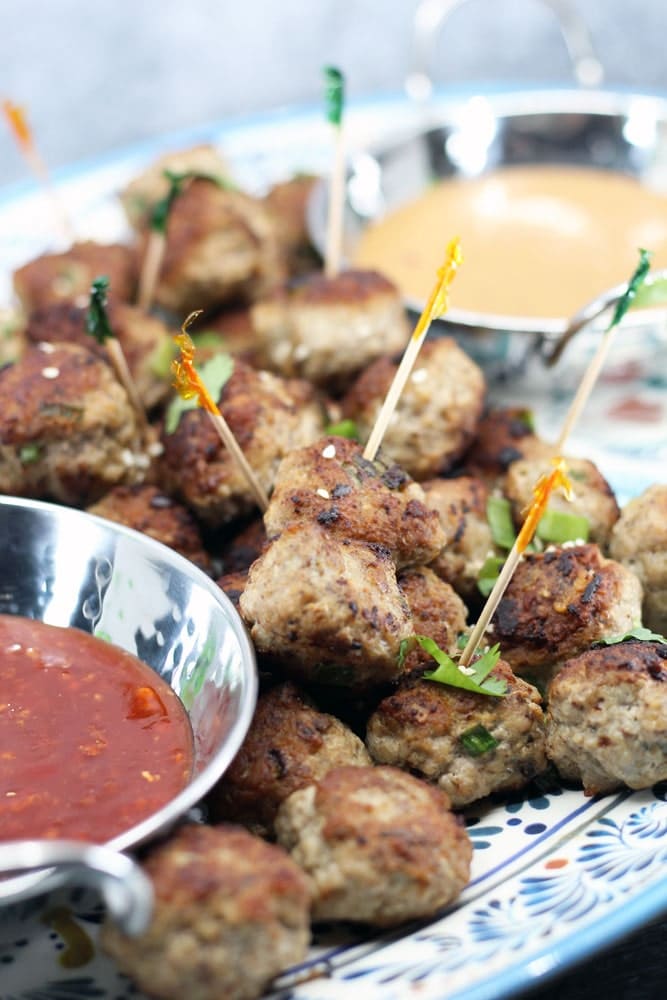 Pork and Mushroom Meatballs piled on a platter with bowls of orange and red sauces