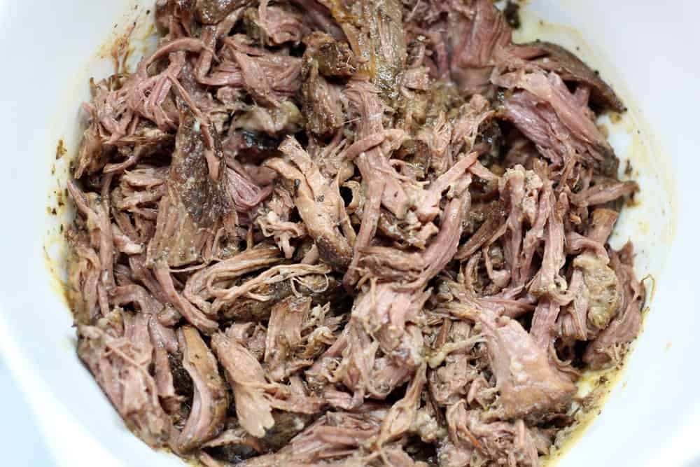 shredded cooked beef in a white mixing bowl
