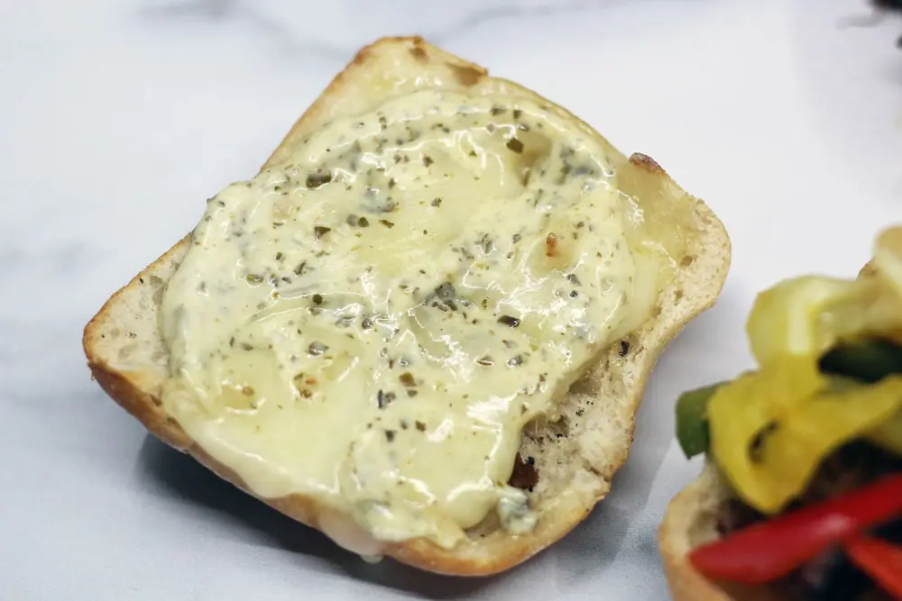 the top portion of a bun upside down and covered in baked melted herbed cheese