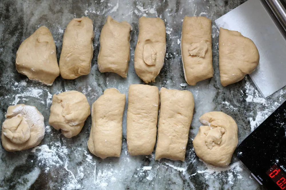 tan colored concha dough being portioned into equal pieces on a floured work surface