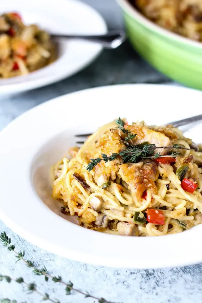 bowl of Chicken Spaghetti or spaghetti noodles covered in a mushroom cream sauce with chicken, onions and peppers and topped with melted cheddar, breadcrumbs, and crispy jalapenos