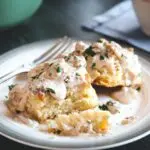 two Buttermilk Biscuits covered in Sausage Gravy with a fork in the background