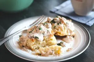 two Buttermilk Biscuits covered in Sausage Gravy with a fork in the background