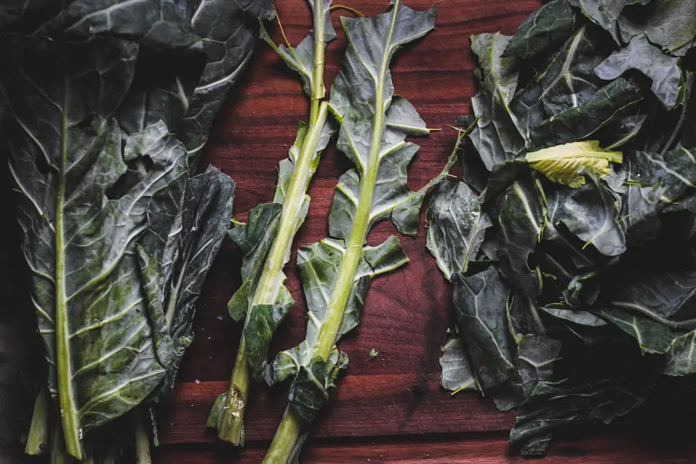 collard greens with the vein removed on a dark wooden cutting board