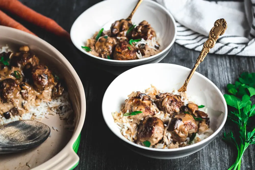 Poor Boy Supper or meatballs in a mushroom gravy over white rice served into two bowls with gold forks