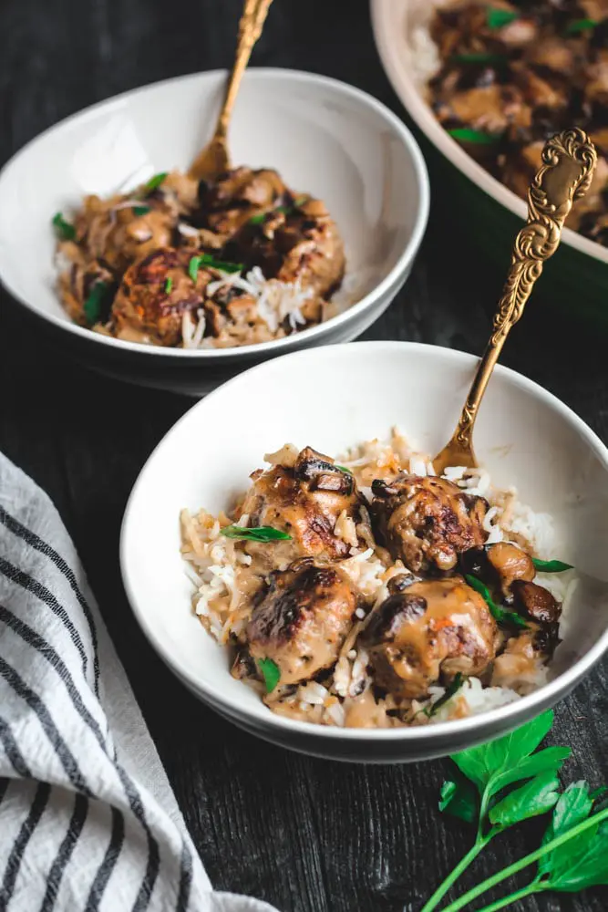 Poor Boy Supper or meatballs in a mushroom gravy over white rice served into two bowls with gold forks