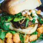 closeup view of a Cilantro Chicken Sandwich with Chili-Spiced Tater Tots on a long rectangular white plate