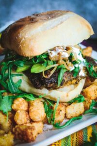 closeup view of a Cilantro Chicken Sandwich with Chili-Spiced Tater Tots on a long rectangular white plate
