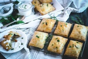 two rows of three shepherd's hand pies on a cooling rack with one pie split open on a small white plate