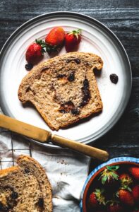 overhead view of a slice of Cinnamon Swirl Bread with a few strawberries on the plate