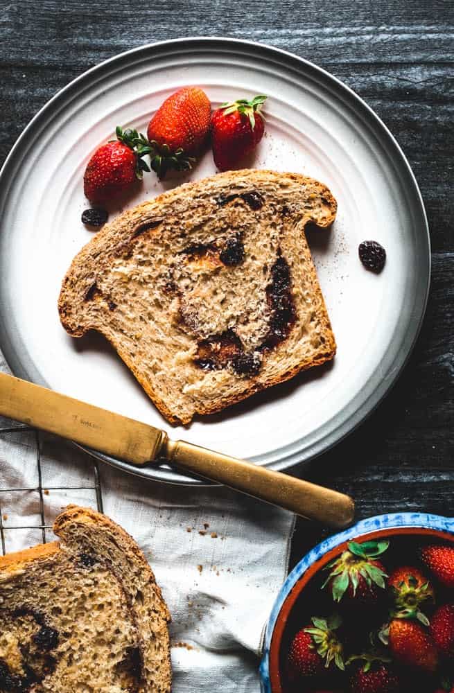 overhead view of a slice of Cinnamon Swirl Bread with a few strawberries on the plate
