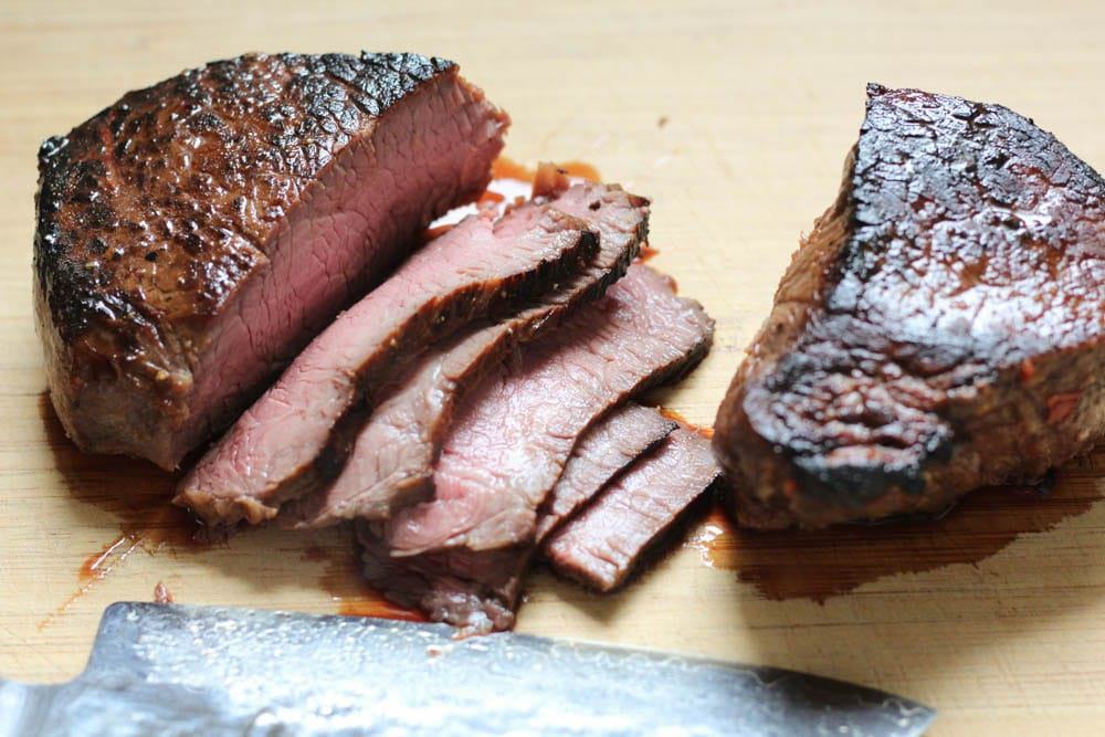 closeup of steak in the process of being sliced showing a pink center